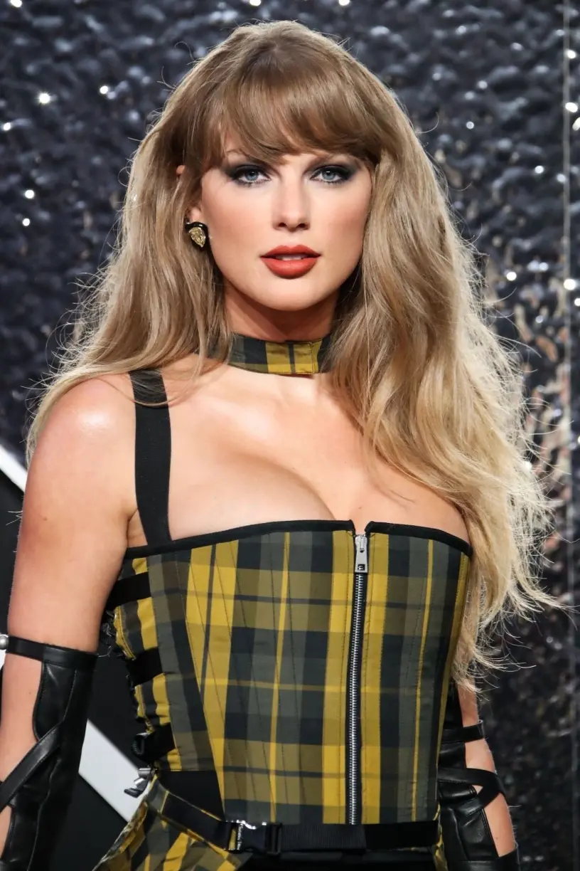 Taylor Swift, at the VMAs, in a plaid dress with a black skirt and black leather boots